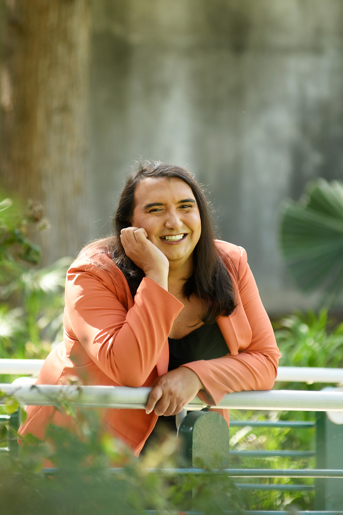Julia, founder of EmberWake, smiling while leaning on a garden railing